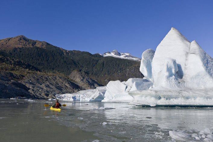 A kayaker paddles the icy waters of Mendenhall Lake on a crisp Fall morning, with Mendenhall Glacier and Mt. Stroller White in the background, Southeast Alaska